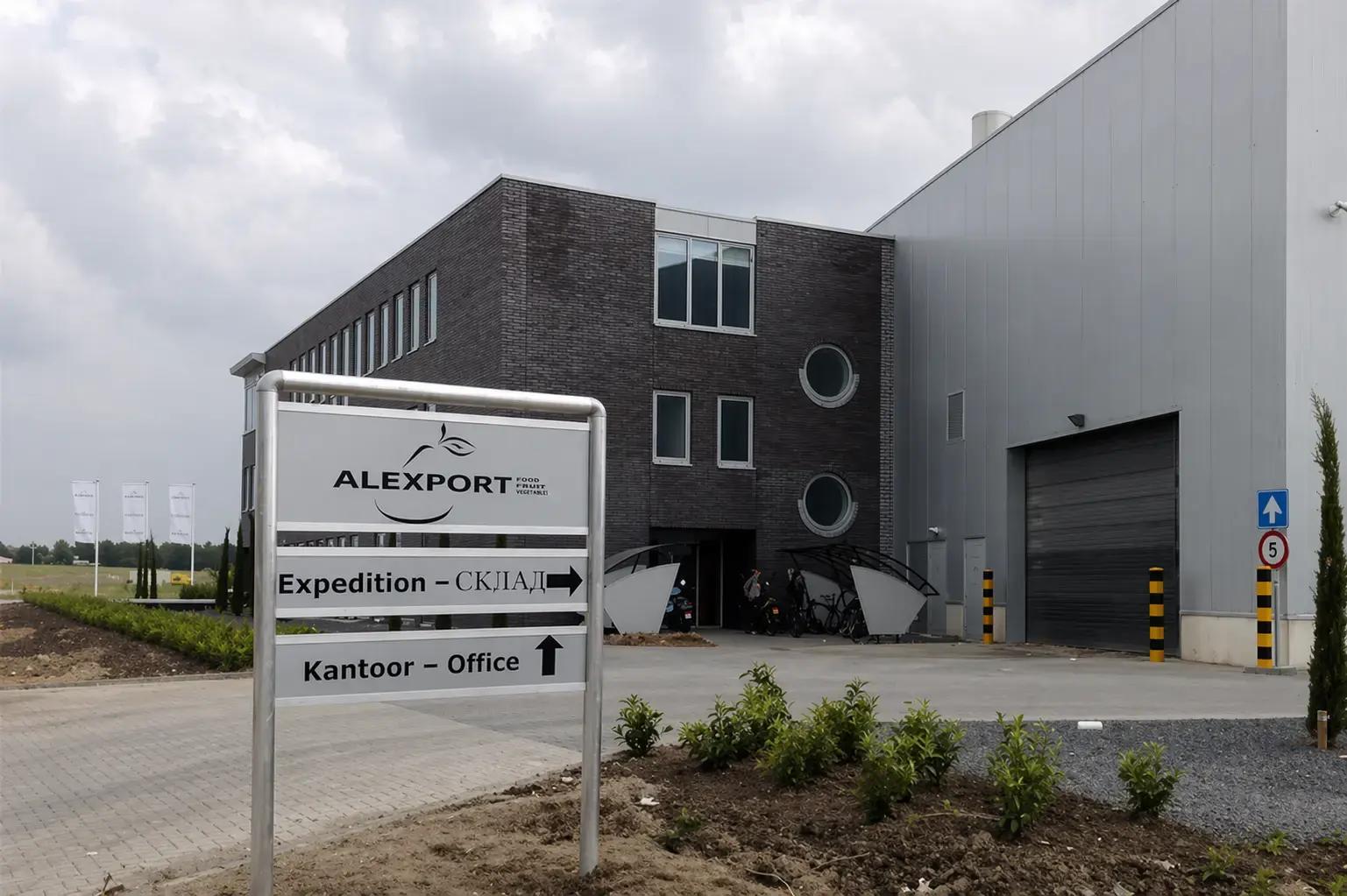 Vrijstaand wayfinding-bord met ALEXPORT-logo, richtingsaanduidingen voor expeditie en kantoor, geplaatst voor een modern bedrijfsgebouw met laadpoort.