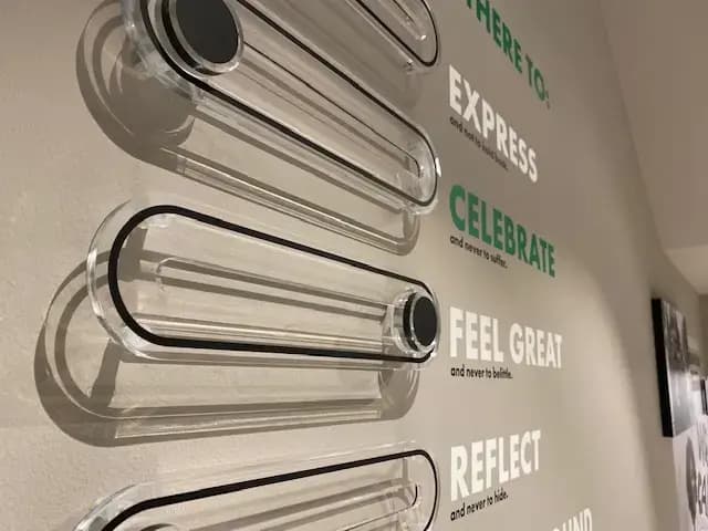 Wanddisplay met transparante acrylaat elementen en typografische interieurbelettering met inspirerende teksten in groen en wit op een lichte binnenwand.