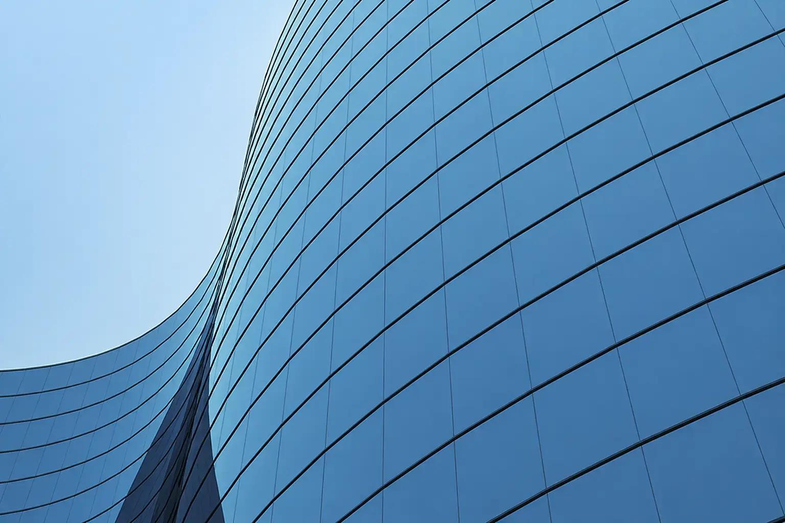 Reflecterende blauwe glasgevel met grote raampanelen op een modern kantoorgebouw.