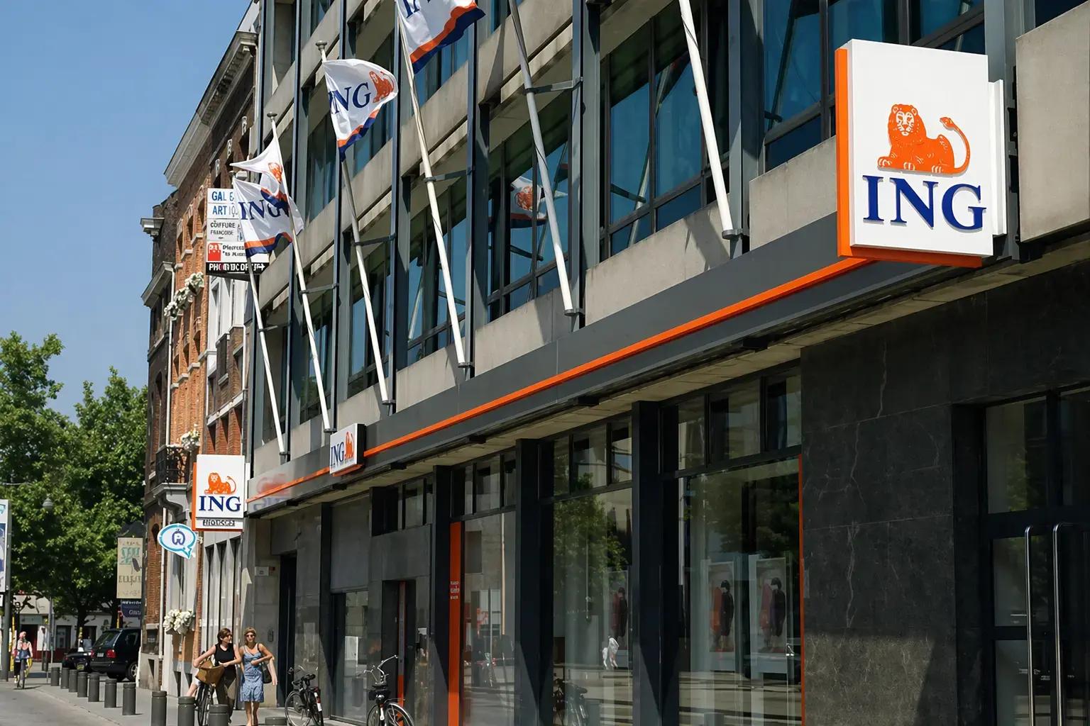 Moderne bankgevel met verlichte ING-uithangborden, gevelbelettering en mastvlaggen aan een glazen kantoorpand in de binnenstad.