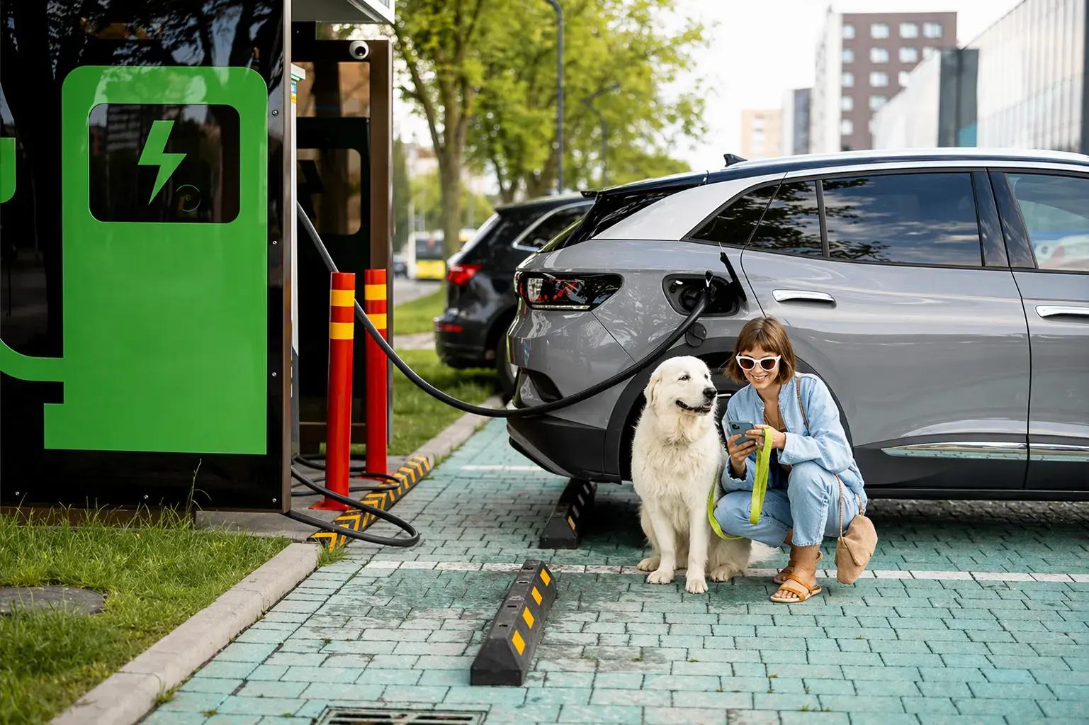 Groene laadpaalbelettering met elektrisch laden pictogram bij een parkeerplaats waar een grijze elektrische auto wordt opgeladen.