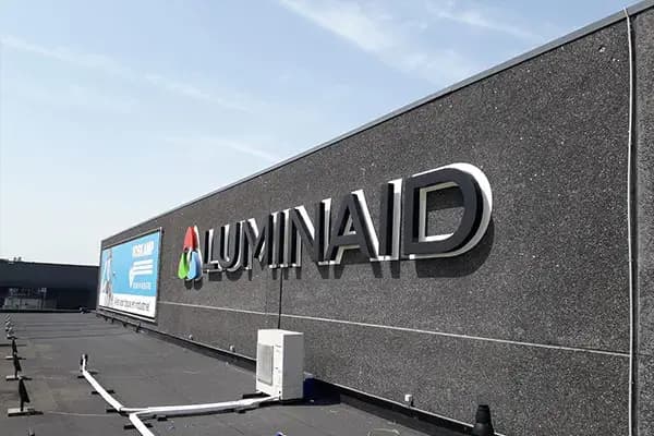 Donkere gevel van een bedrijfspand met gevelreclame van Luminaid, bestaande uit een full-colour logo en zwarte 3D doosletters op een plat dak.