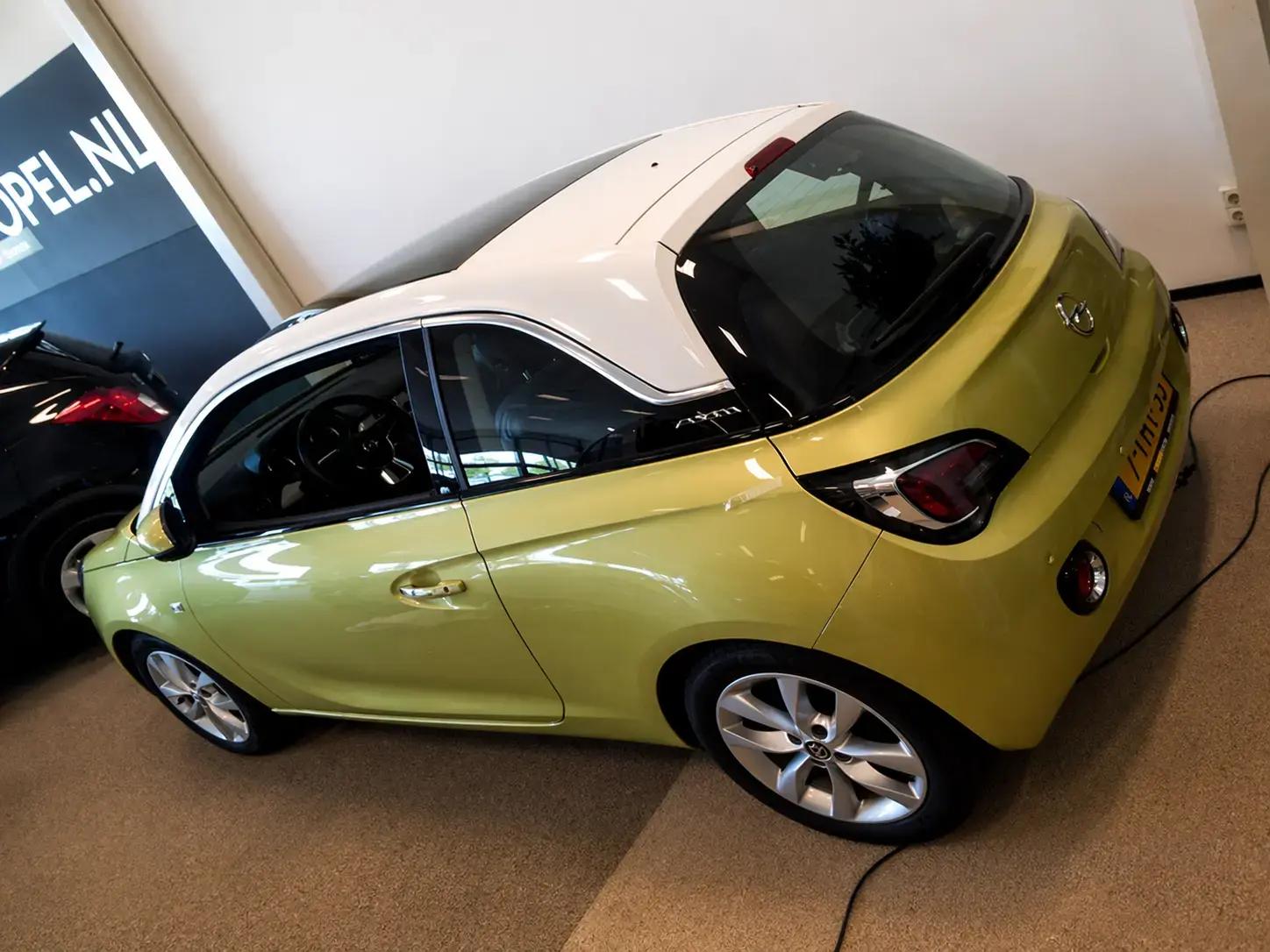 Geelgroene Opel Adam met wit dak en zwarte raampartijen, schuin van boven gefotografeerd in een showroom.