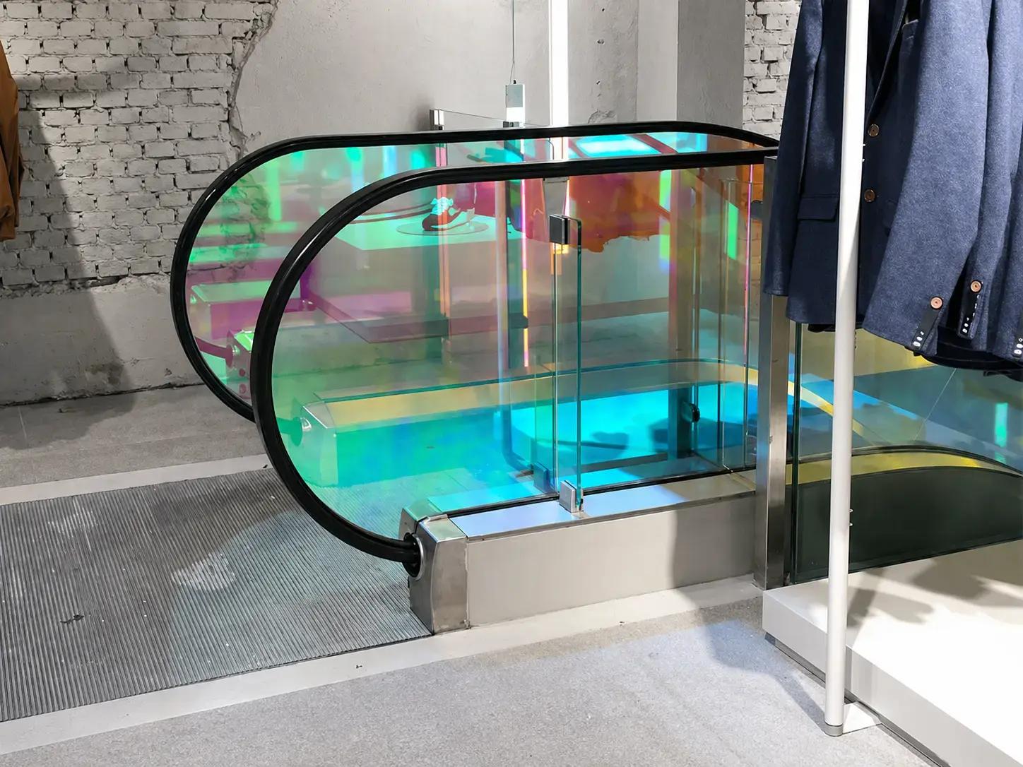 Roltrap in winkelinterieur met transparante iriserende glasfolie op de balustrade, toegepast als kleurrijke decoratieve folie en interieurvisual.