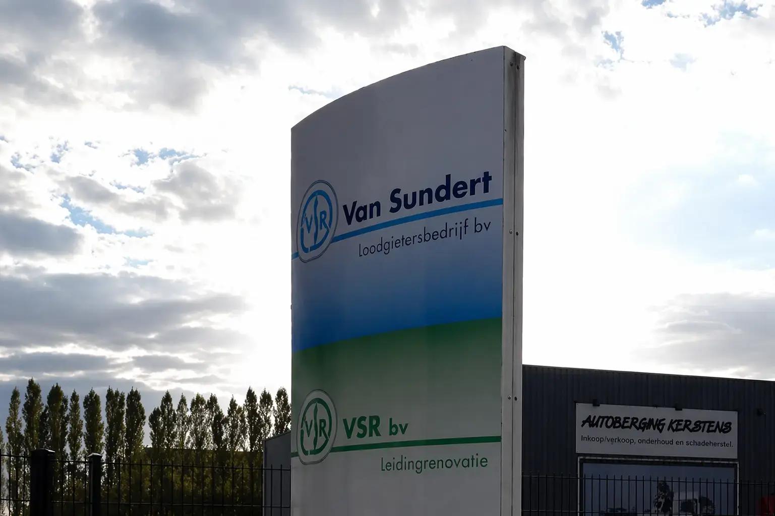 Vrijstaande reclamezuil met Van Sundert Loodgietersbedrijf bv en VSR bv Leidingrenovatie bij een bedrijventerrein.