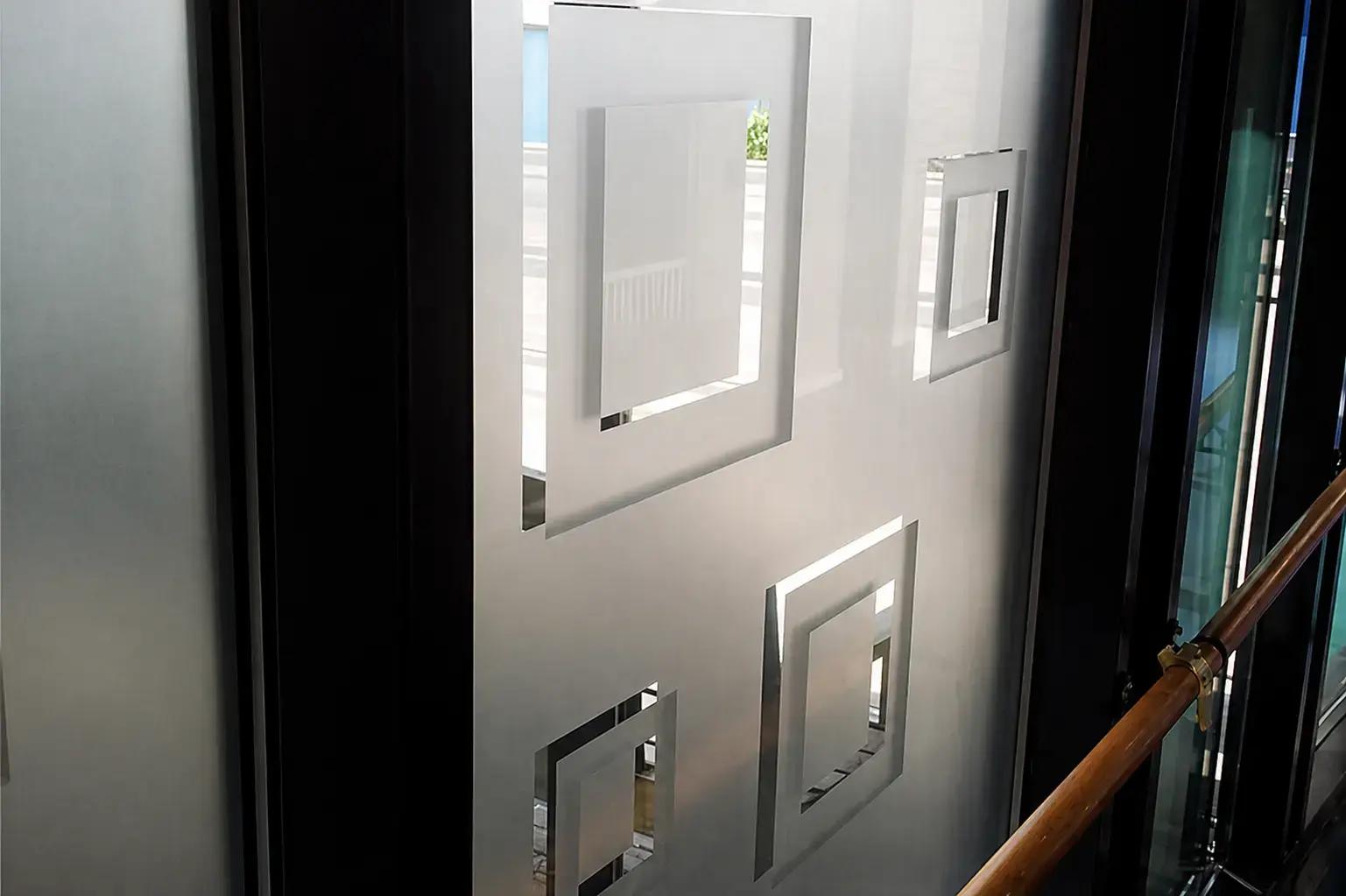 Matte glasfolie met geometrische vierkante uitsparingen op een glazen wand langs een trapleuning.