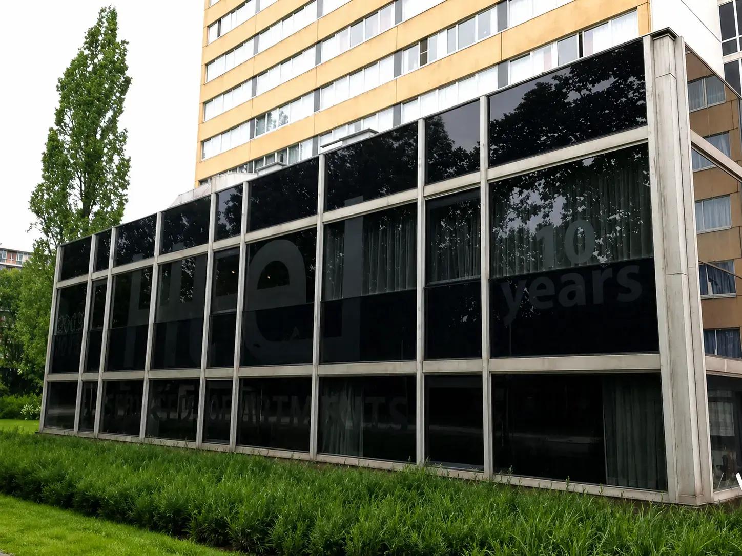 Gevel met donkere raamfolie en grote ton-sur-ton raambelettering op een glazen pui, toegepast als subtiele buitenreclame voor een gebouw.