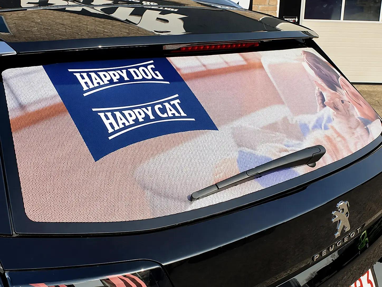 Zwarte personenauto met geperforeerde achterruitfolie en full-colour voertuigbelettering voor diervoeding, voorzien van merklogo’s en fotoprint op de achterruit.