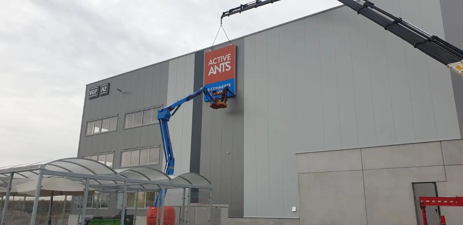 Montage van de Active Ants-doeklichtbak aan het logistieke pand met kraan en hoogwerker.