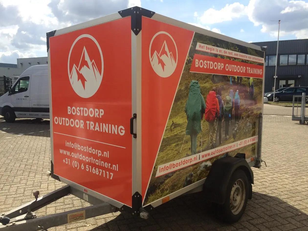 Bostdorp Outdoor Training trailer with orange branding and a large photographic print on its side.