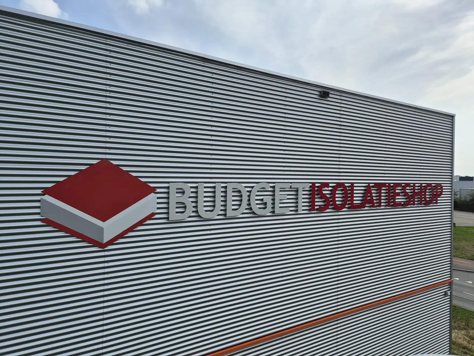 Breed overzicht van het logo en de bedrijfsnaam Budget Isolatieshop op de metalen gevelbekleding.