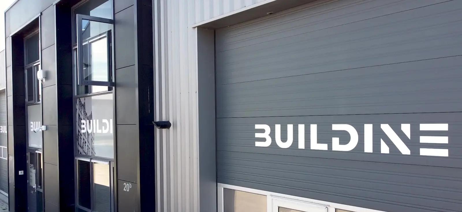 Wit Buildine-logo op een grijze roldeur