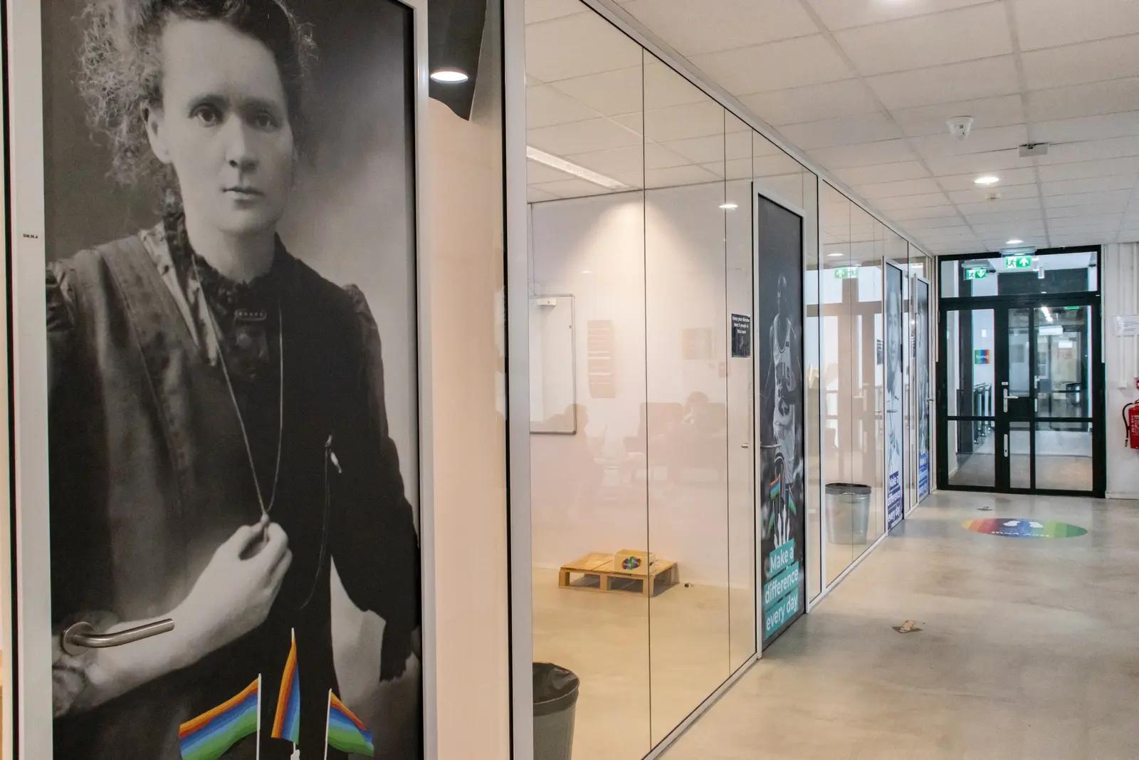 Door print with a Marie Curie portrait beside the glazed corridor