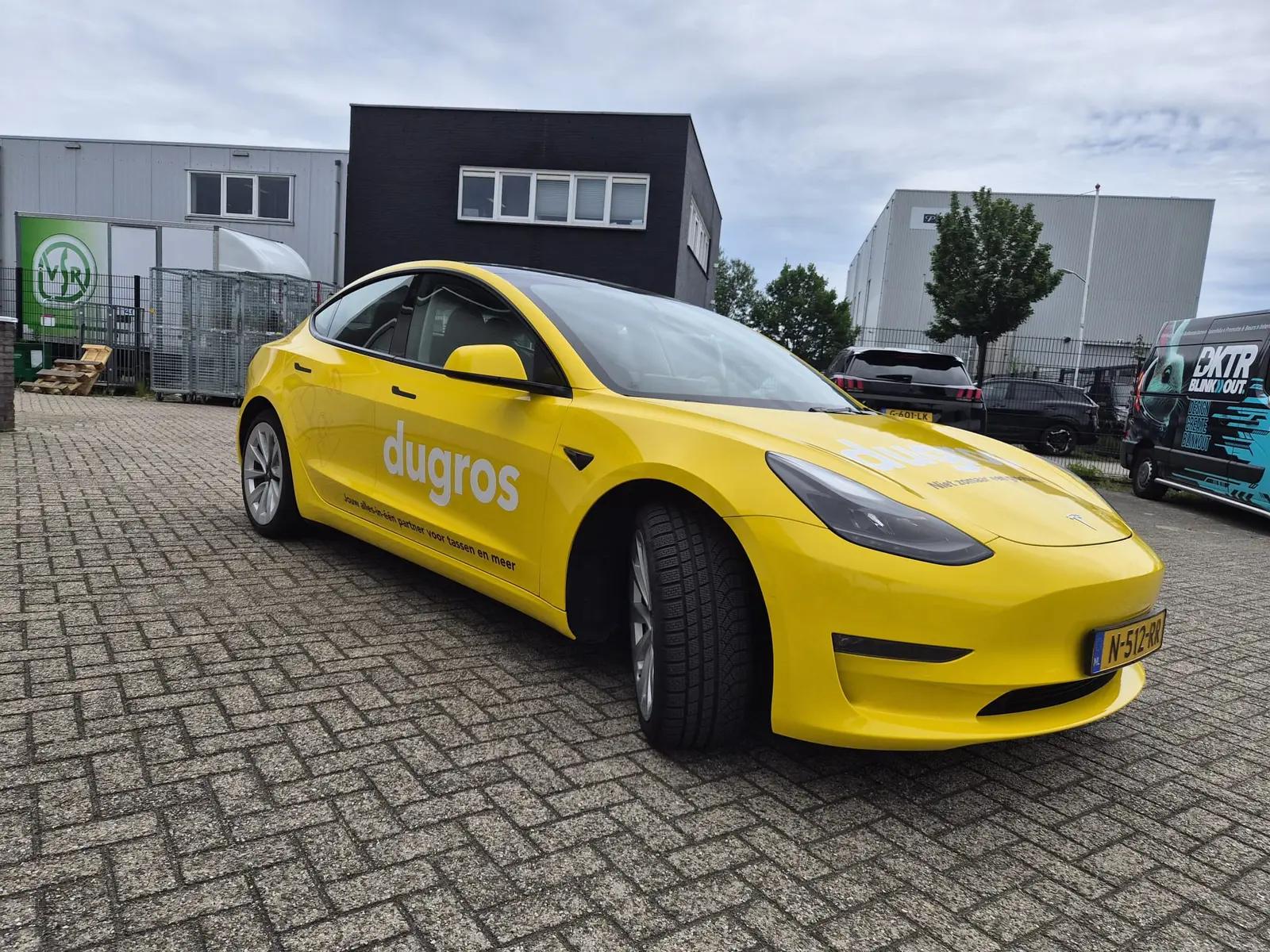 Yellow Tesla Model 3 with a white Dugros logo and black strapline, viewed from the front quarter.