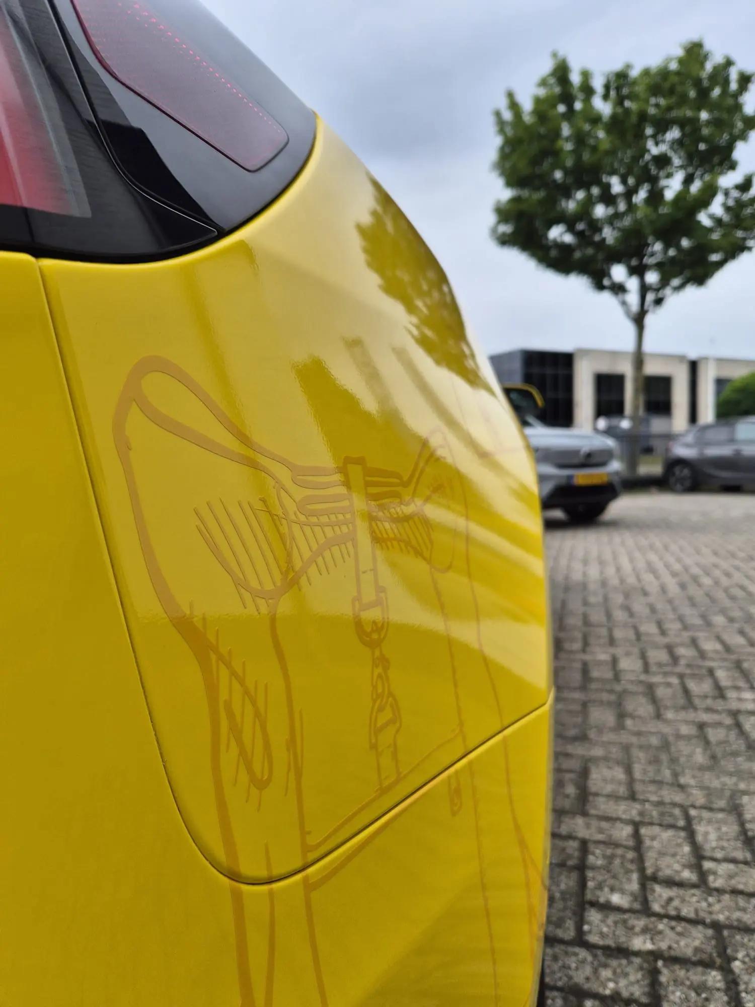 Detail van de gele wrap en donkergele tasillustratie rond de laadklep en het achterlicht van de Dugros Tesla.