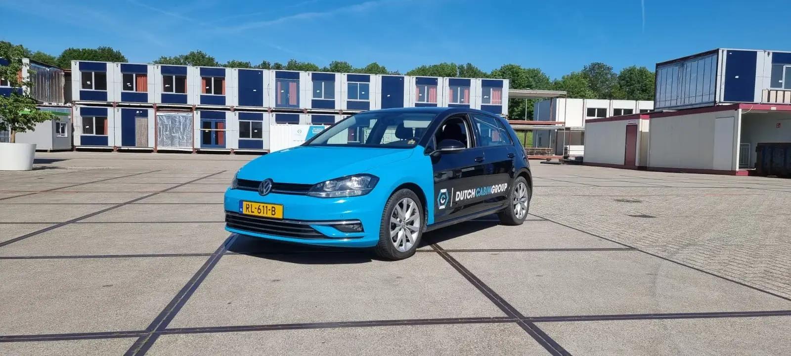 Volkswagen Golf with blue and dark blue Dutch Cabin Group graphics.