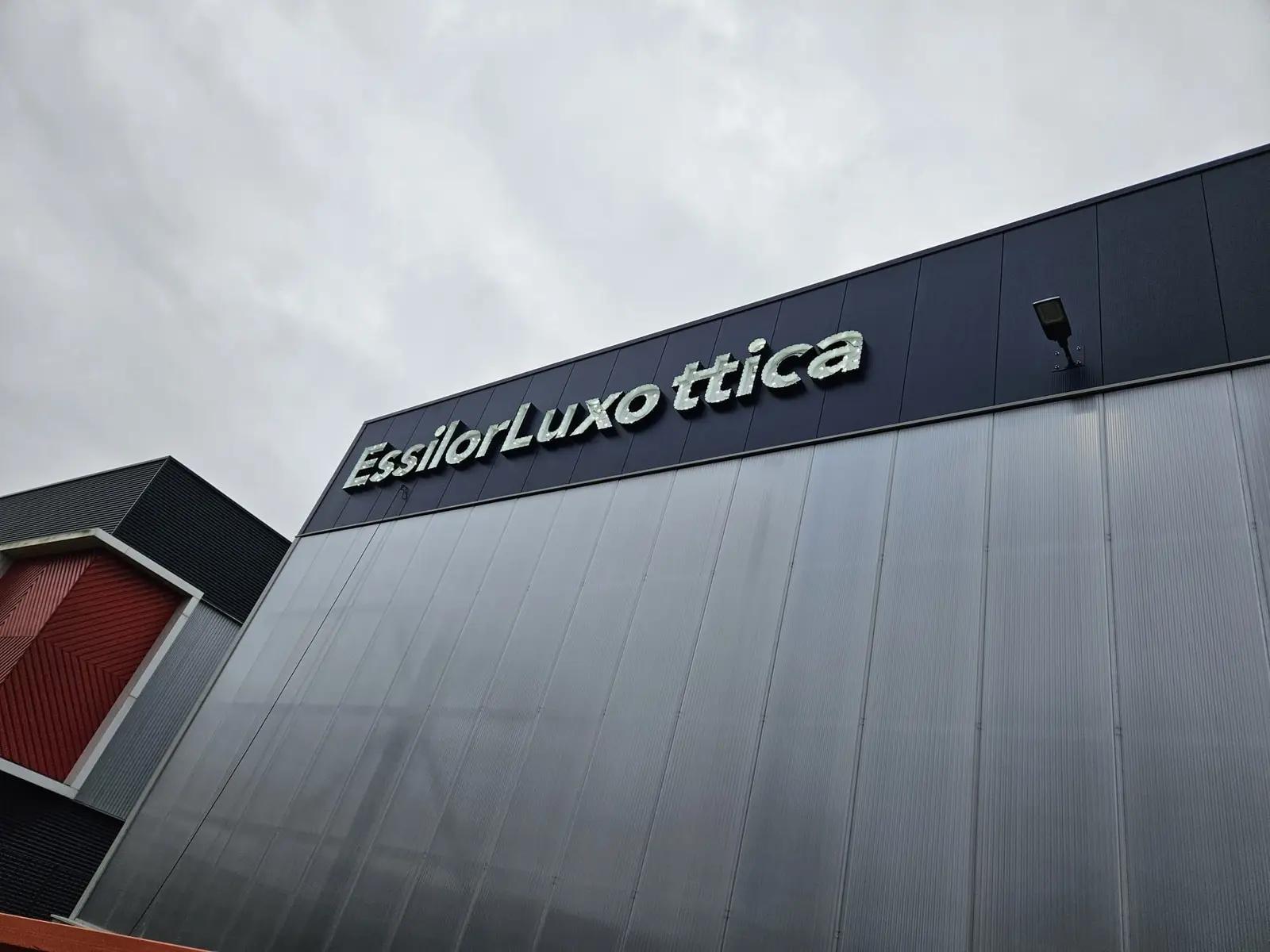 EssilorLuxottica-doosletters tegen de donkere gevelband tijdens de montage.