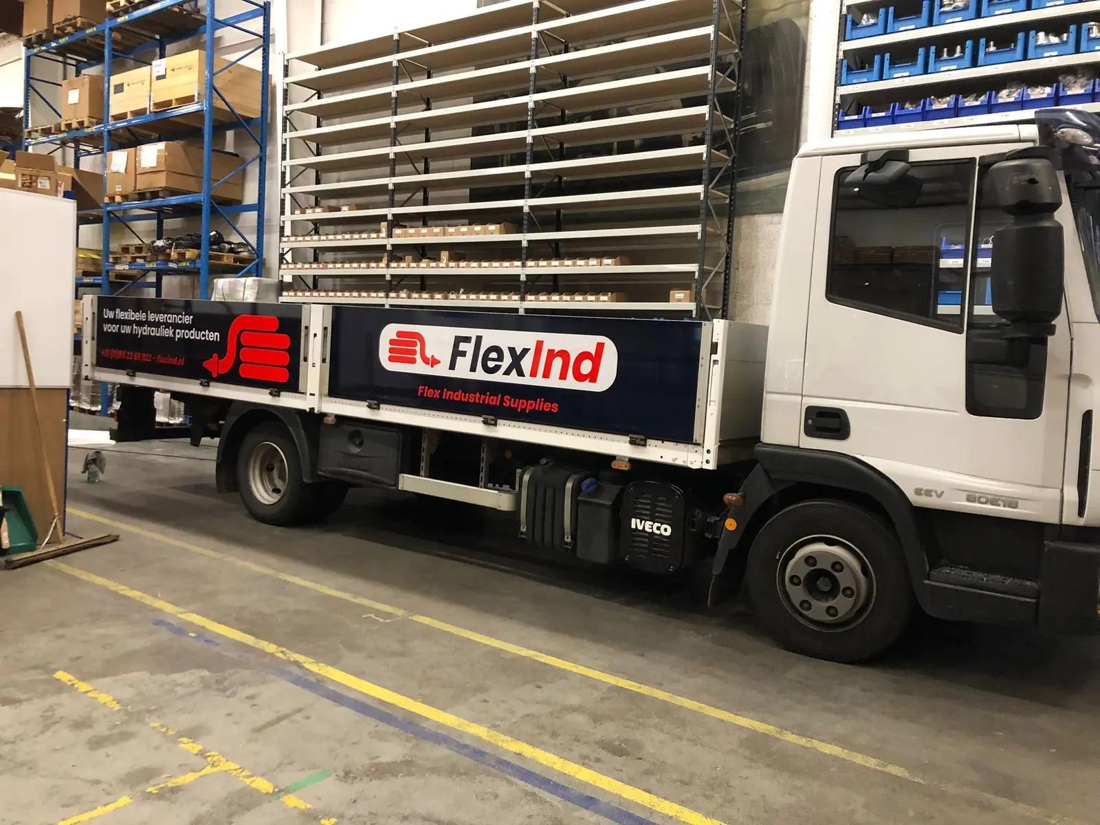 FlexInd-bedrijfswagen met rood-witte belettering op een donkere ondergrond.