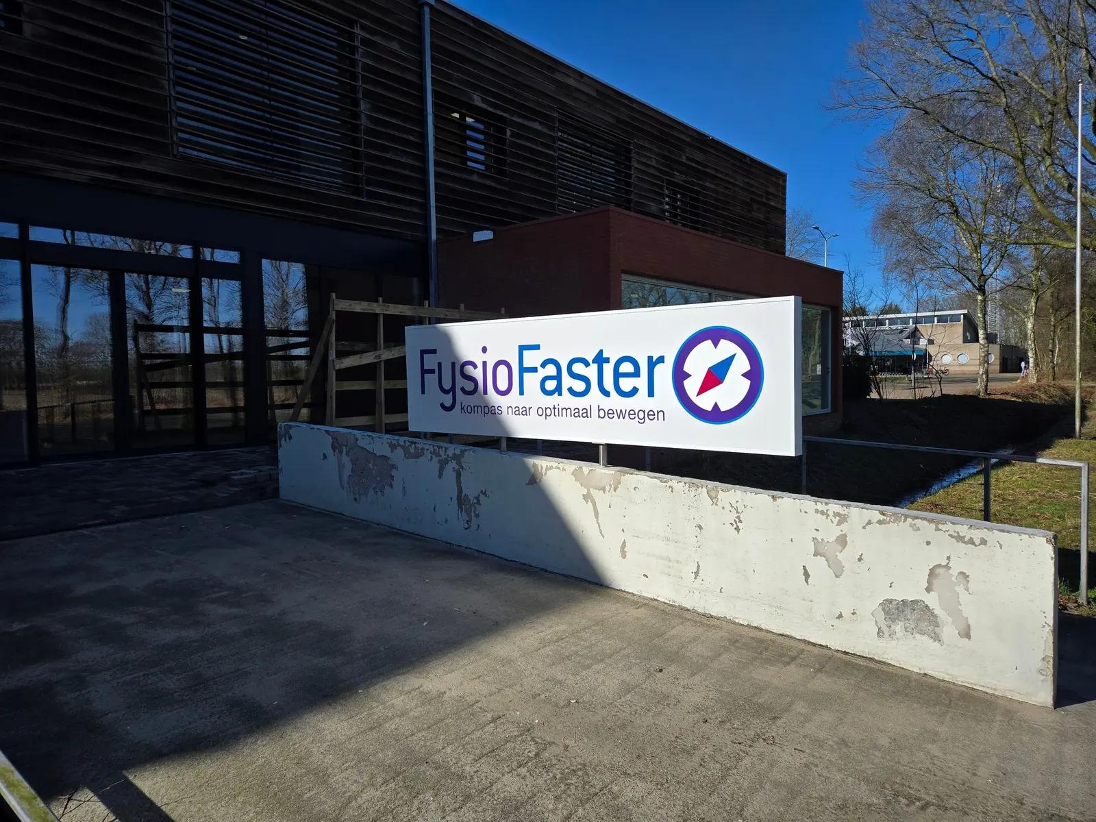 FysioFaster-lichtreclame met het gekleurde kompaslogo naast de toegang tot de praktijk.