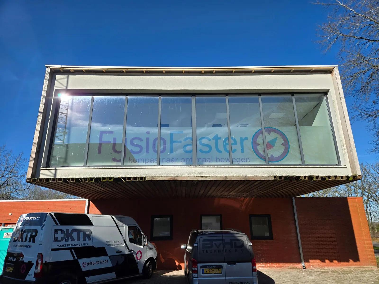 FysioFaster-naam en kompas op de glaspartij aan de voorzijde van het gebouw.