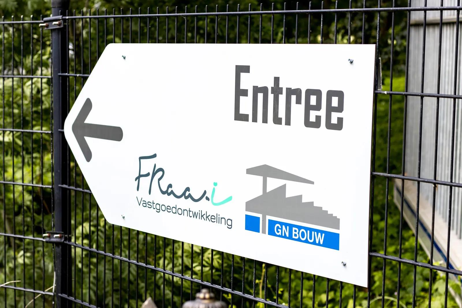 White entrance sign with black arrow on the fence