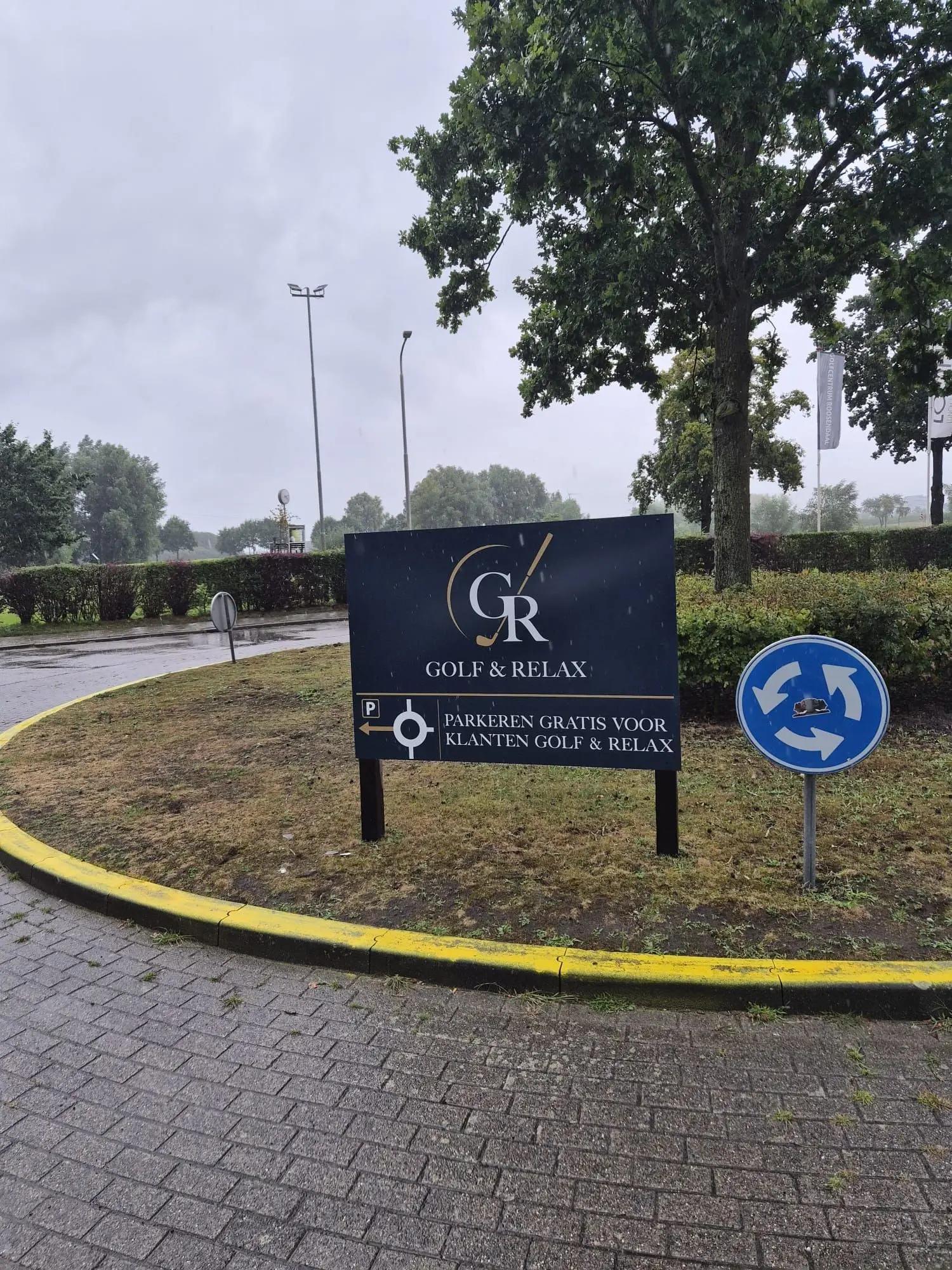 Blauw-wit Golf & Relax-bord met goudkleurige accenten langs de toegangsroute.