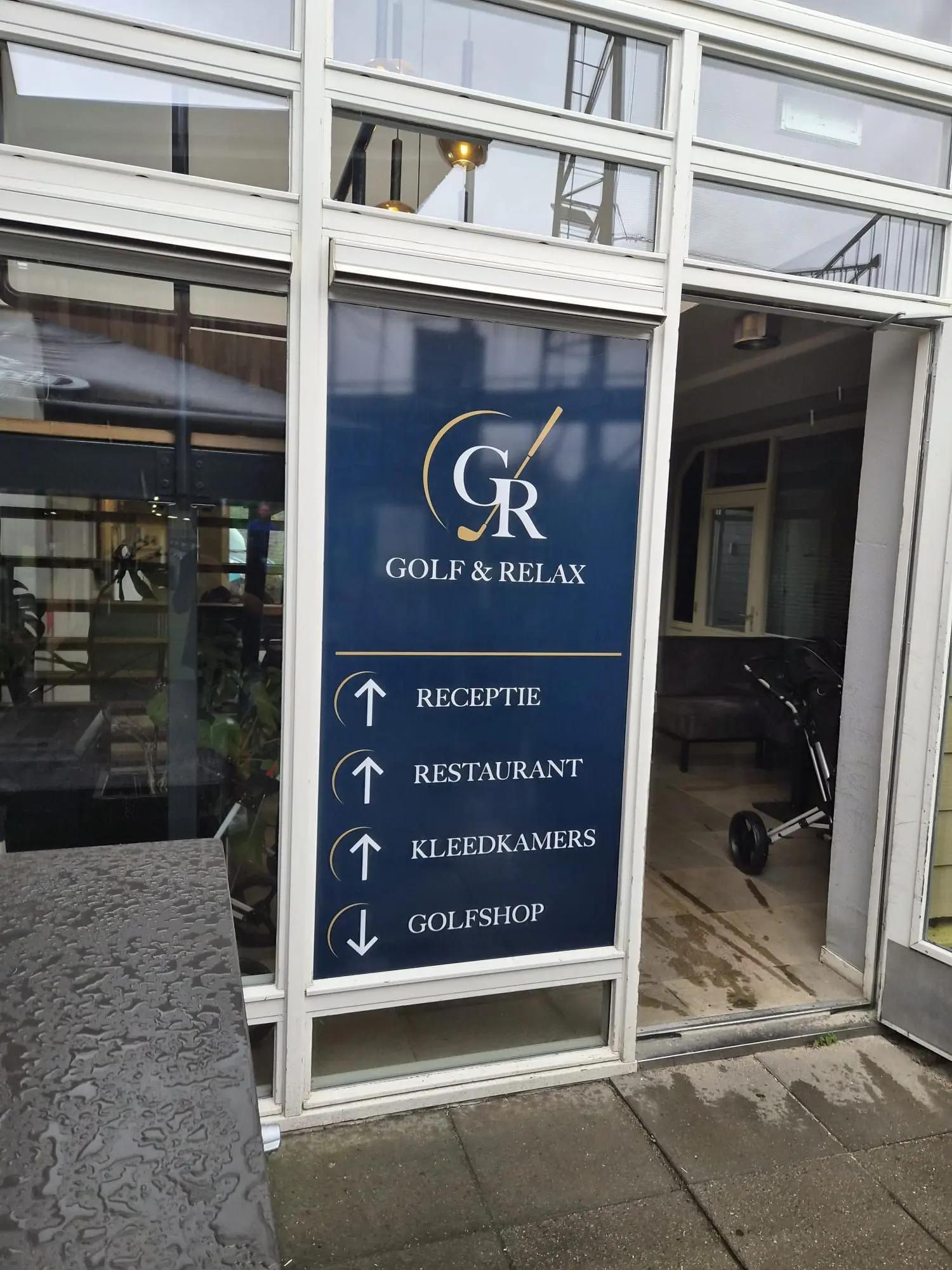 Blauwe raambestickering met verwijzingen naar receptie, restaurant, kleedkamers en golfshop.
