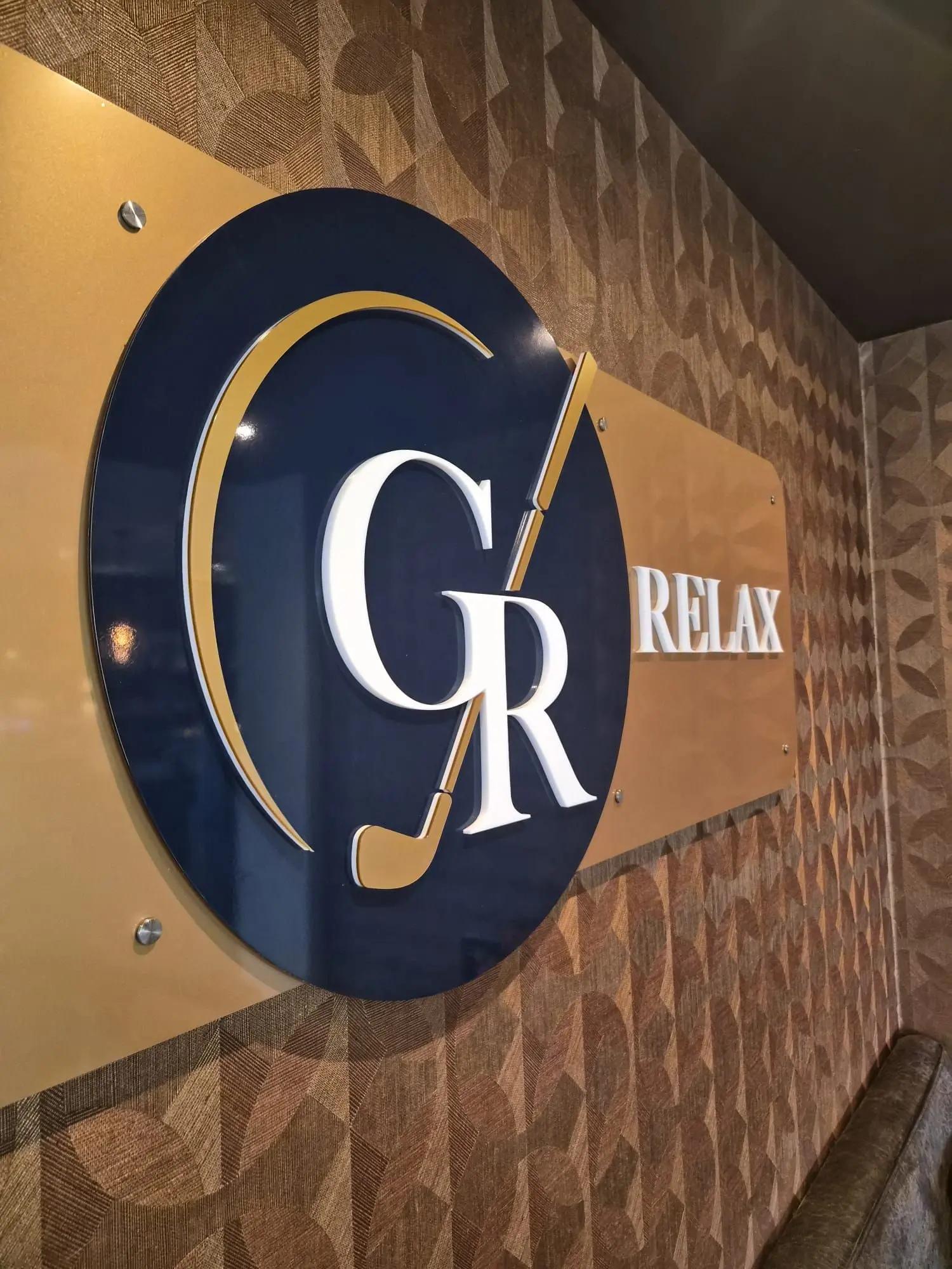 Detail van het ruimtelijke Golf & Relax-logo met goudkleurige drager en afstandhouders.