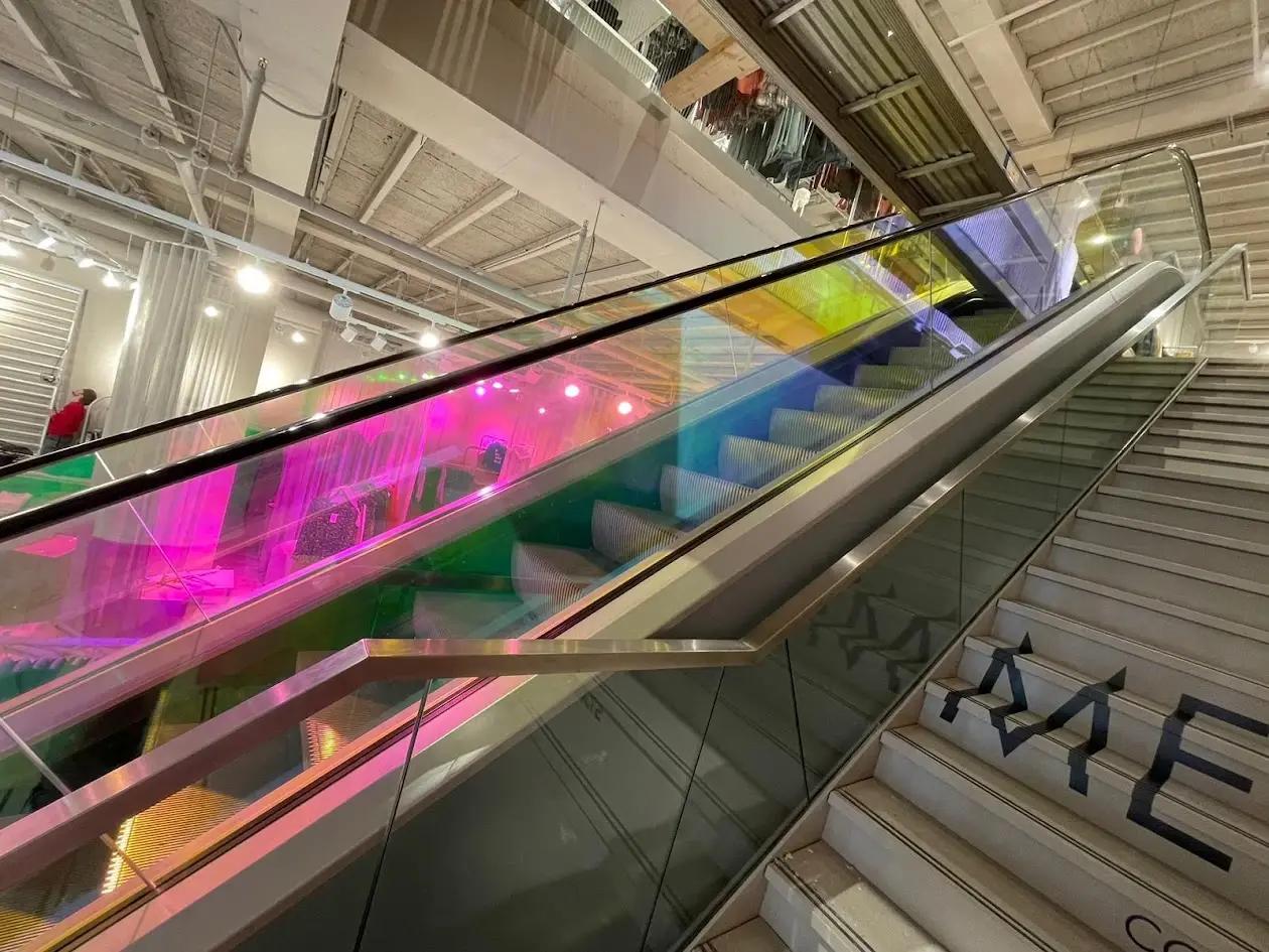 Dichroic glass film with shifting colours on a glass escalator balustrade
