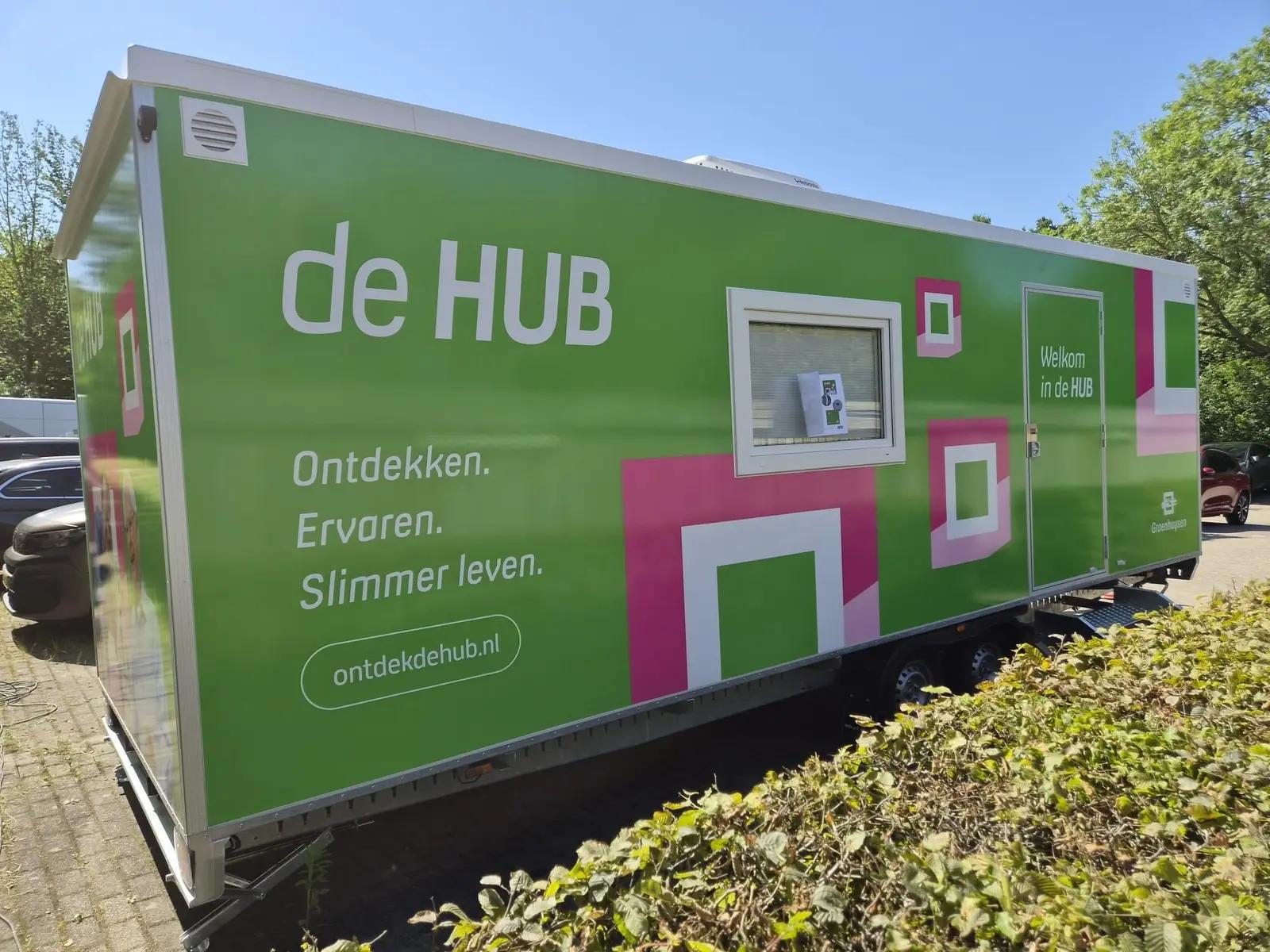 Groene HUB Express-aanhanger met logo en herkenbare graphics rond de deur.