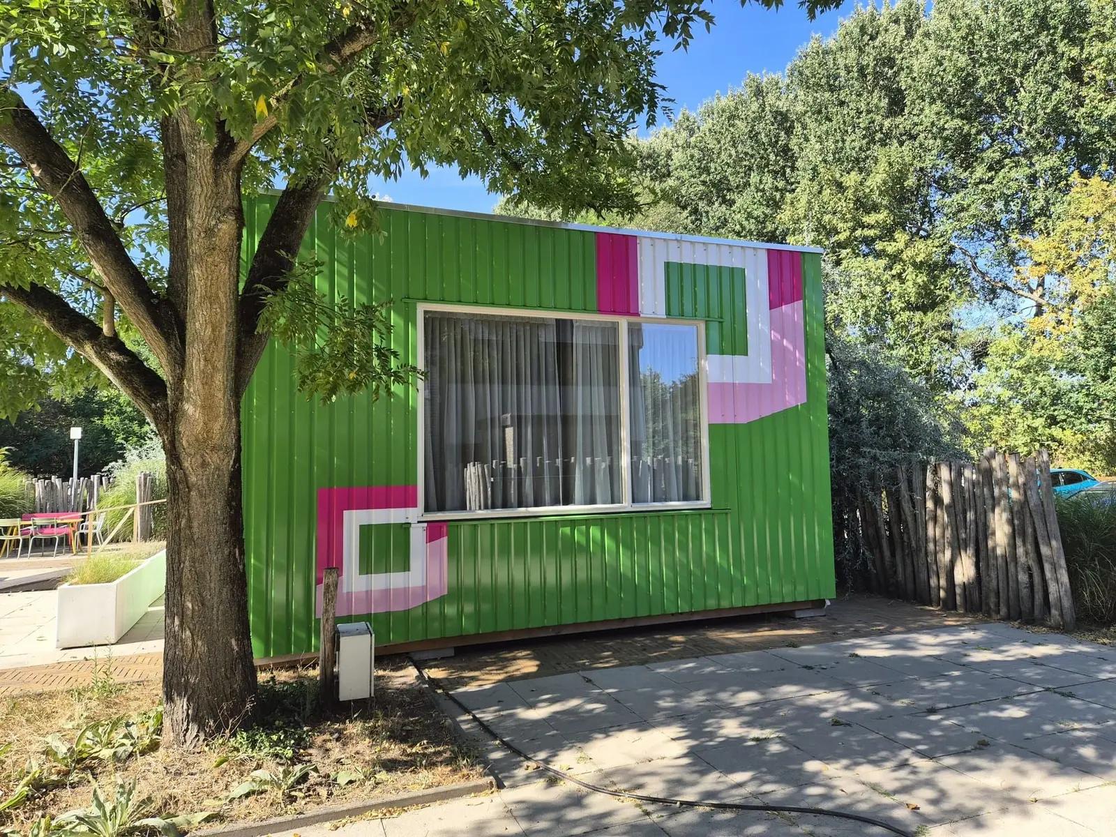 Raamzijde van de HUB Studio met groene bekleding en grote roze en witte vormen.
