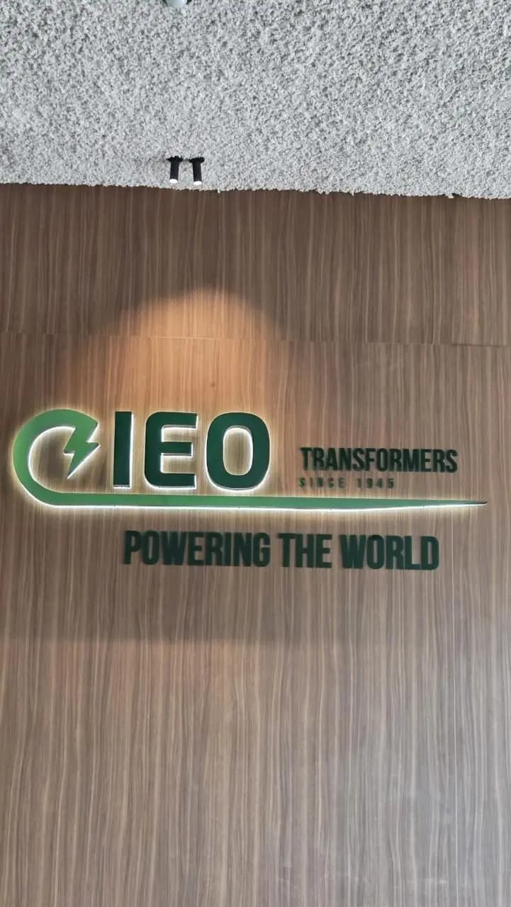 Vooraanzicht van de IEO-interieurletters en de lichtgloed op de houten wand.