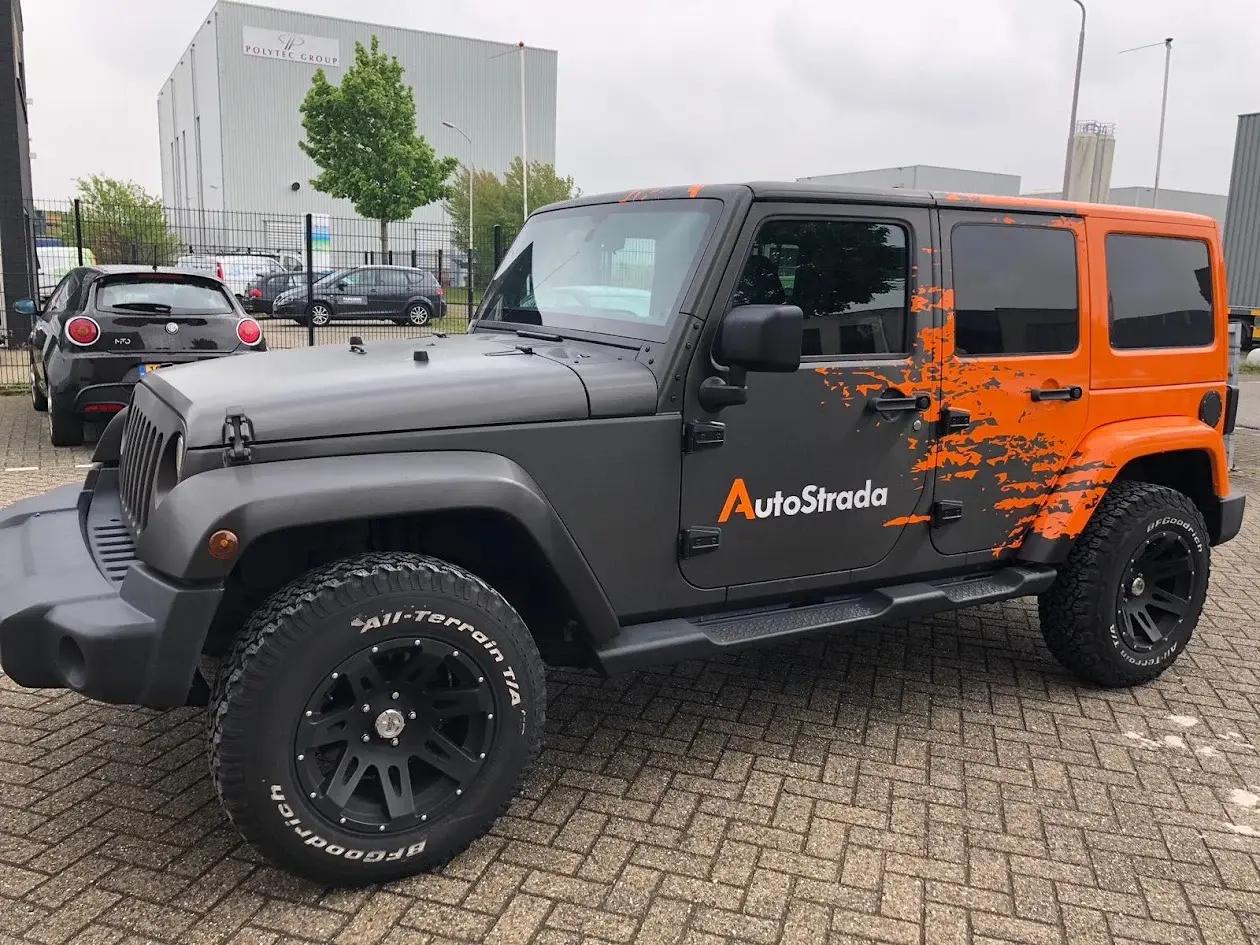 Jeep with grey and orange AutoStrada advertising graphics.