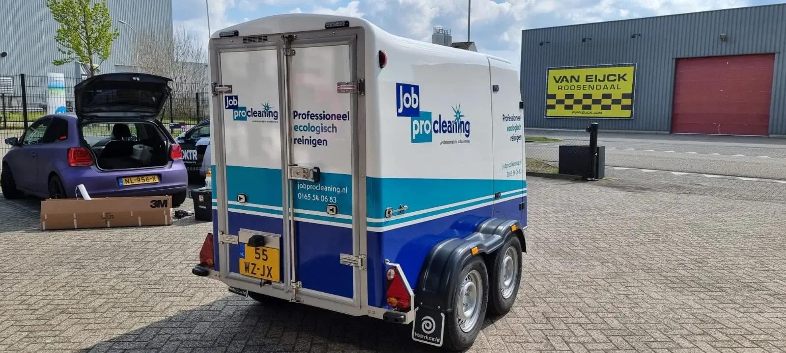Enclosed Job Procleaning trailer with blue and turquoise graphics on its side and rear doors.