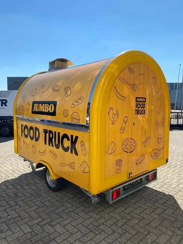 Yellow Jumbo food trailer viewed from the side and rear, with black FOOD TRUCK lettering and food illustrations.