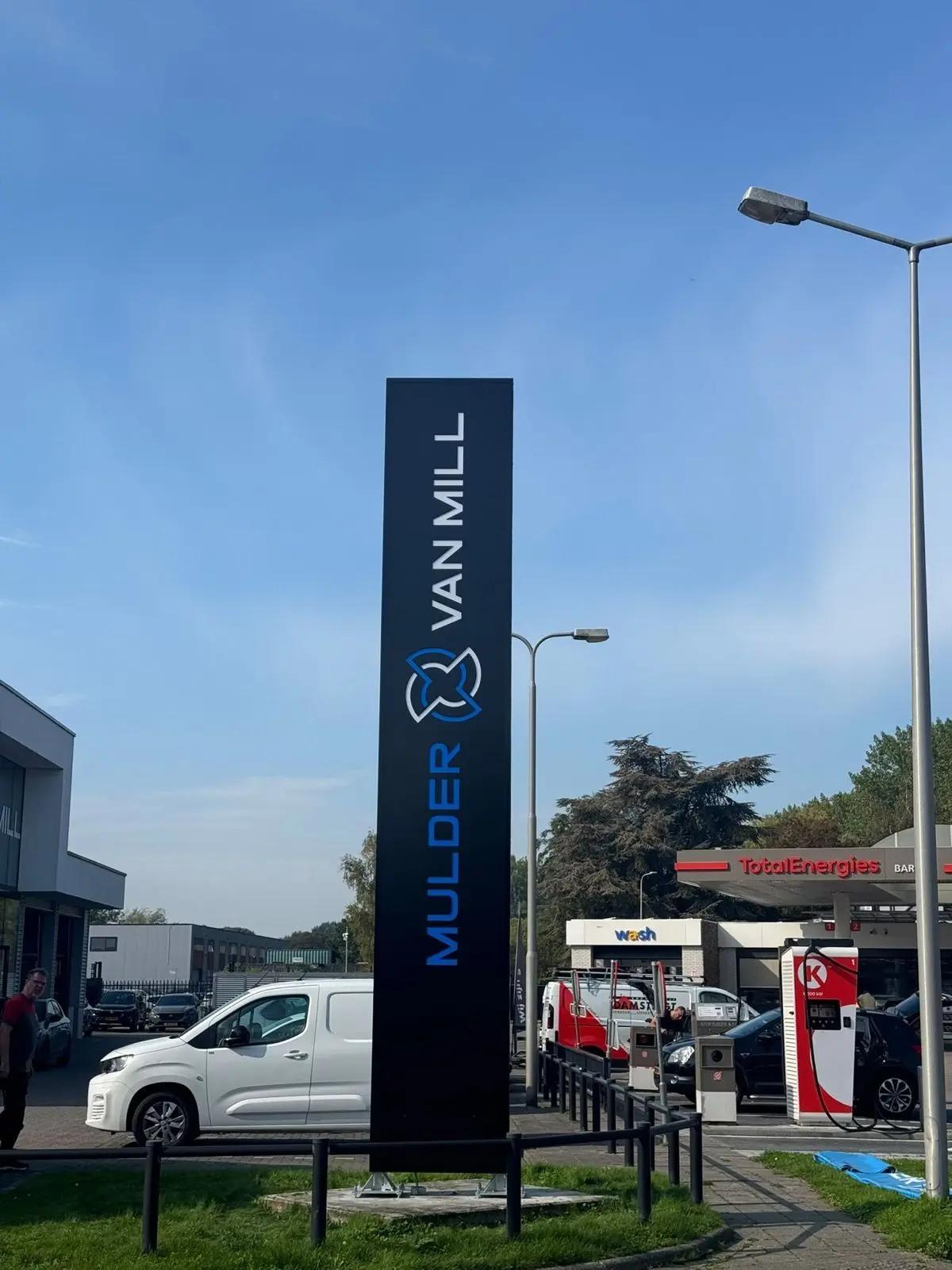 Vooraanzicht van de geplaatste reclamezuil bij de weg en showroom.