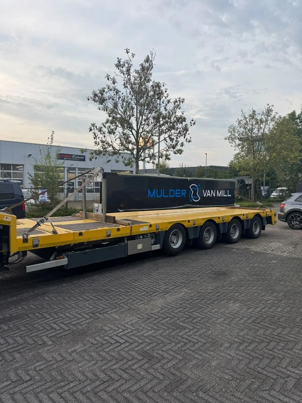 The signage pylon lies on a low-loader for transport and installation.