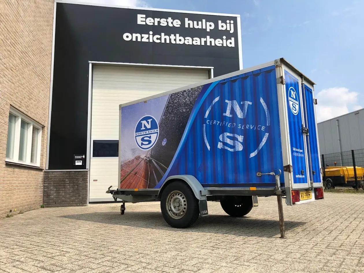 Blue North Sails trailer with full-colour graphics outside the BlinkOut workshop.