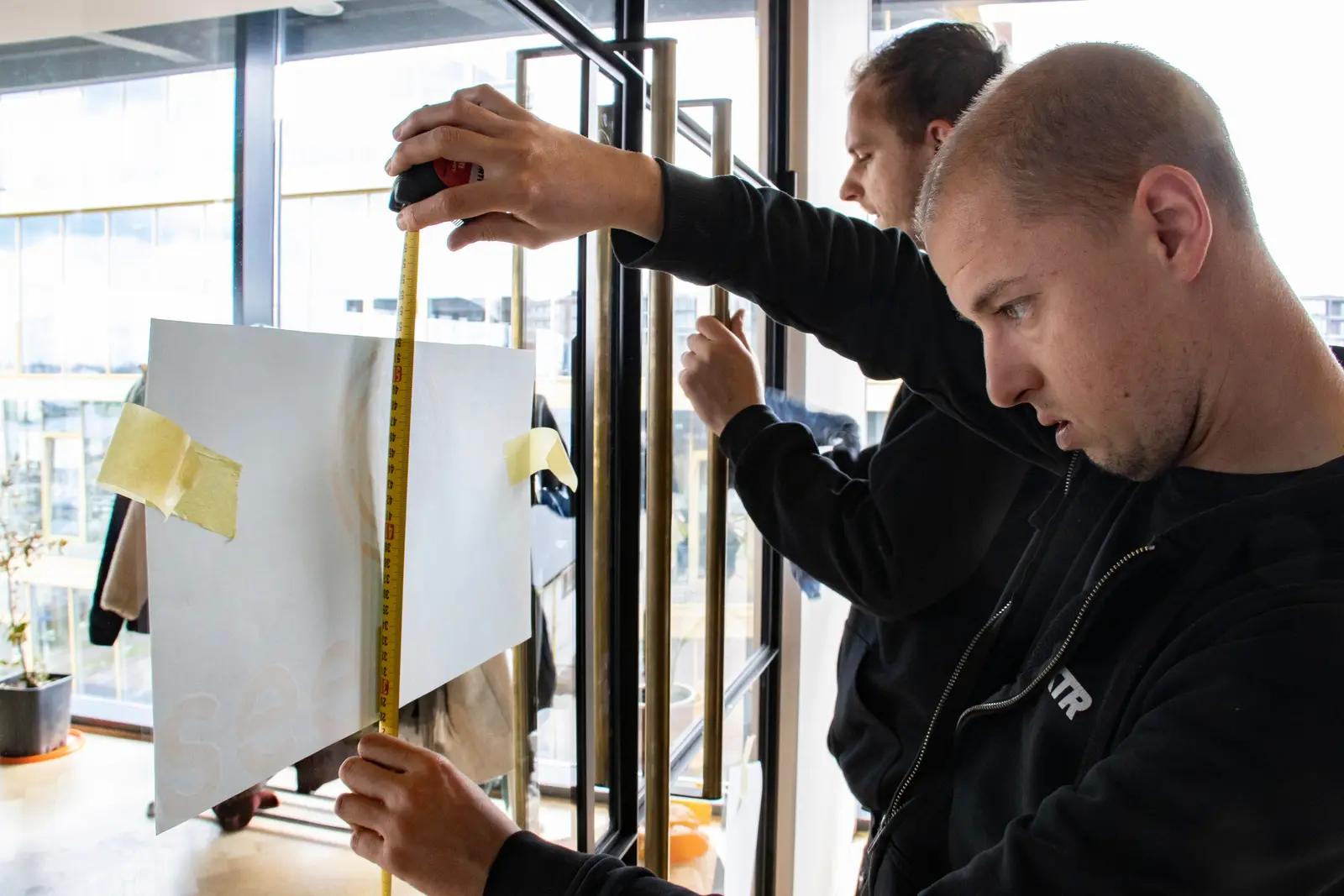 Montage van de glasgraphics in het Seenons-kantoor