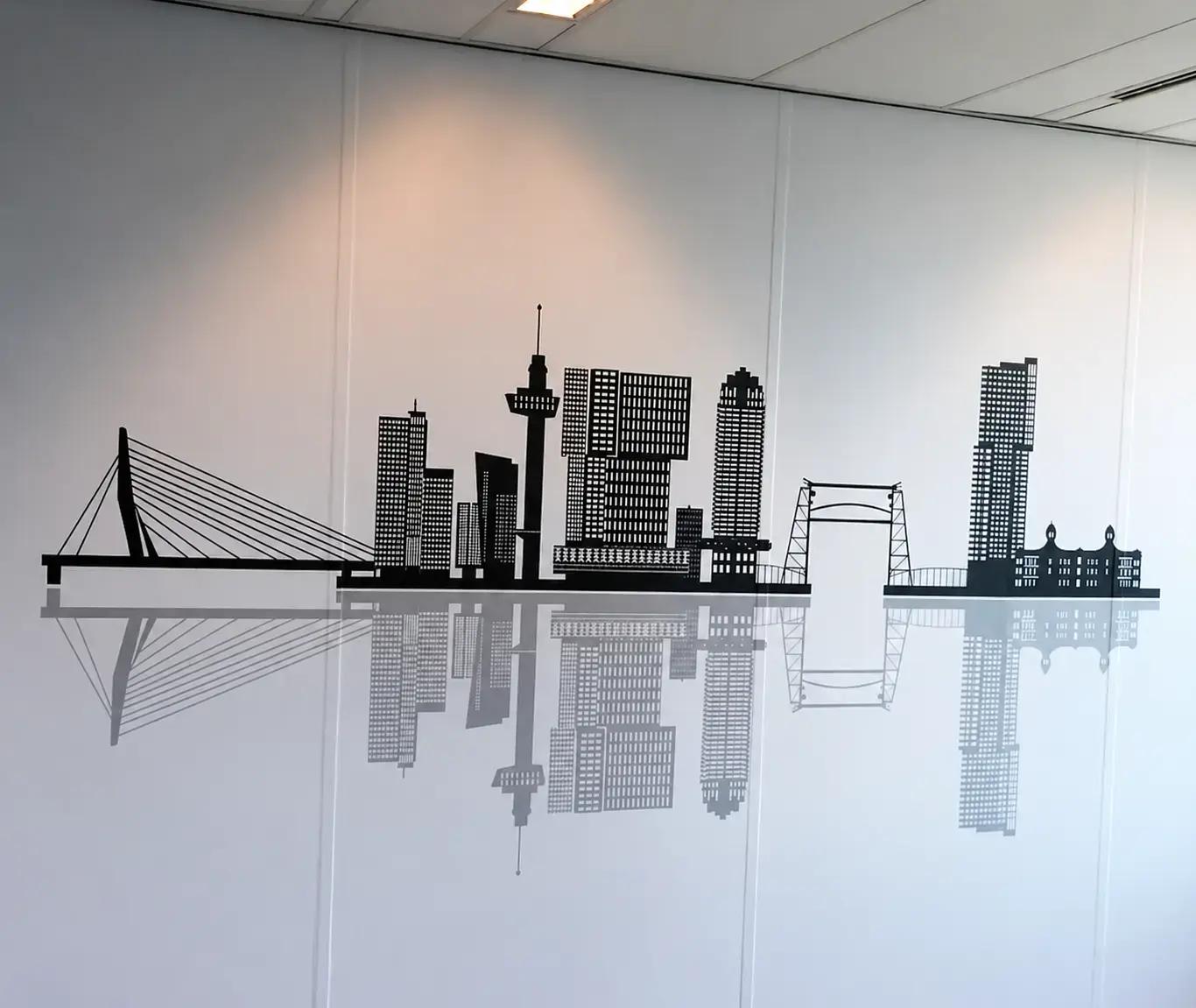 Wanddecoratie met zwarte skyline en spiegeling op een witte binnenmuur, toegepast als minimalistische interieurbelettering en kantoorvisual.