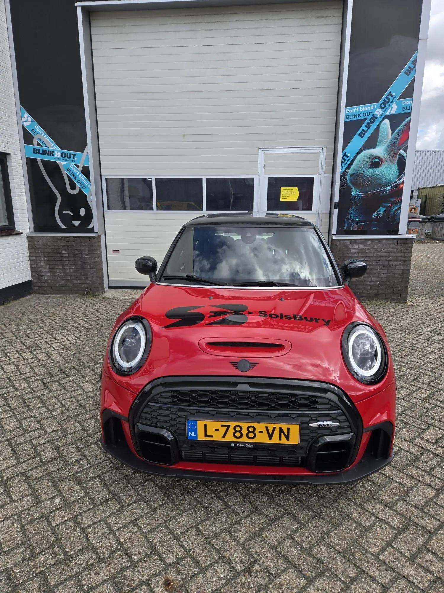 Vooraanzicht van de rode Mini met zwarte Solsbury-graphics op de motorkap.