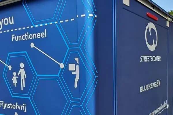 Close-up van blauwe voertuigbelettering op een bedrijfswagen met hexagonpatroon, pictogrammen en witte merk- en functietekst op het zijpaneel.