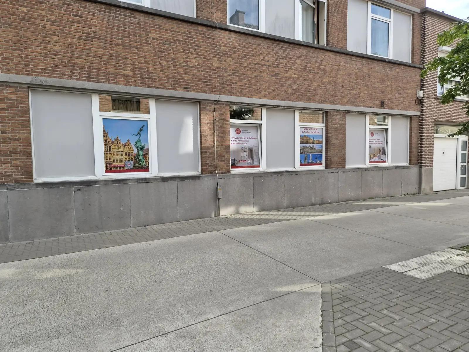 Bedrukte ramen van Budget Flats Leuven met stadsbeelden en een welkomstboodschap.