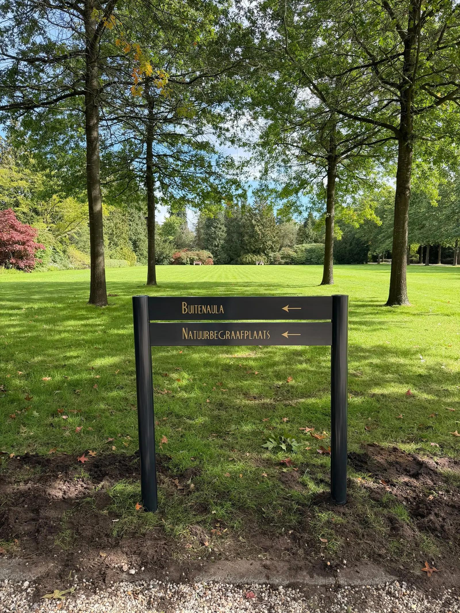 Low directional sign on two posts with arrows towards Betula and the natural burial ground.