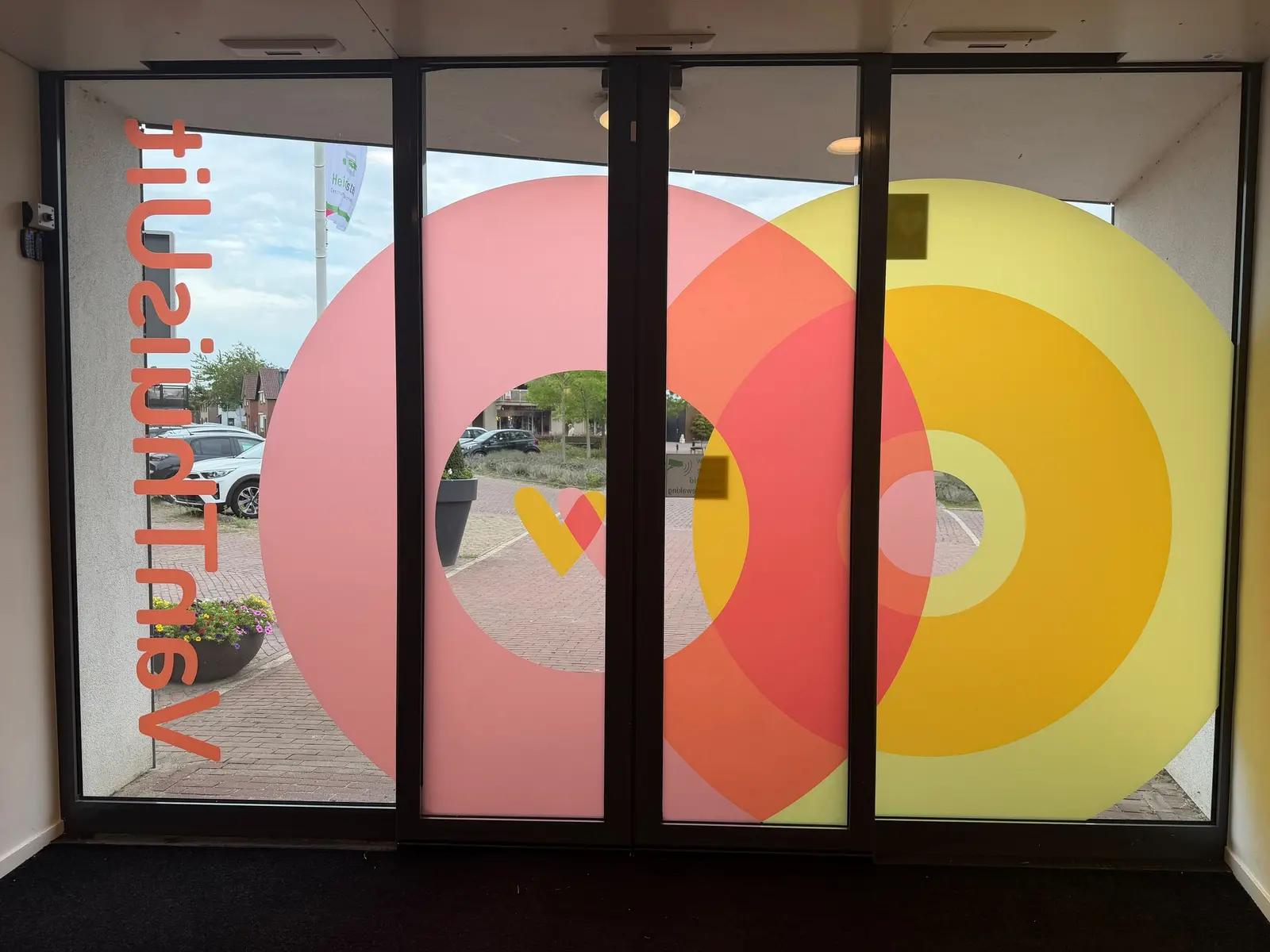 Printed window film with large overlapping circles on the VanThuisUit entrance, viewed from inside.