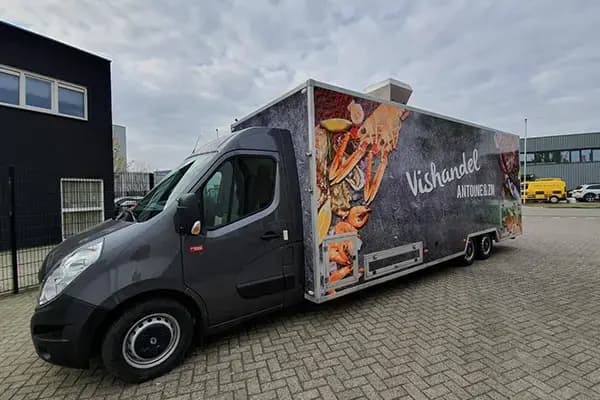 Donkergrijze verkoopwagen met full-colour voertuigbelettering voor Vishandel Antoine & Zn, voorzien van grote fotoprints van vis en schaaldieren op de zijkant.