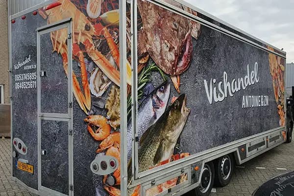 Verkoopwagen met full-colour voertuigbelettering voor Vishandel Antoine & Zn, voorzien van grote fotoprints van vis en schaaldieren en opvallende merkbelettering op de zijkant en achterdeur.