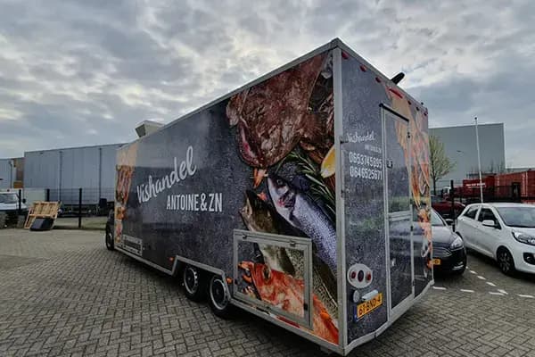 Grote verkoopwagen met full-colour voertuigbelettering voor Vishandel Antoine & Zn, voorzien van fotoprints van vis en schaaldieren op de zijkanten en achterzijde.