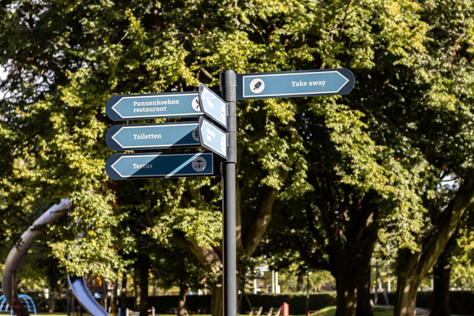 Directional signs to Vrouwenhof destinations amongst the trees