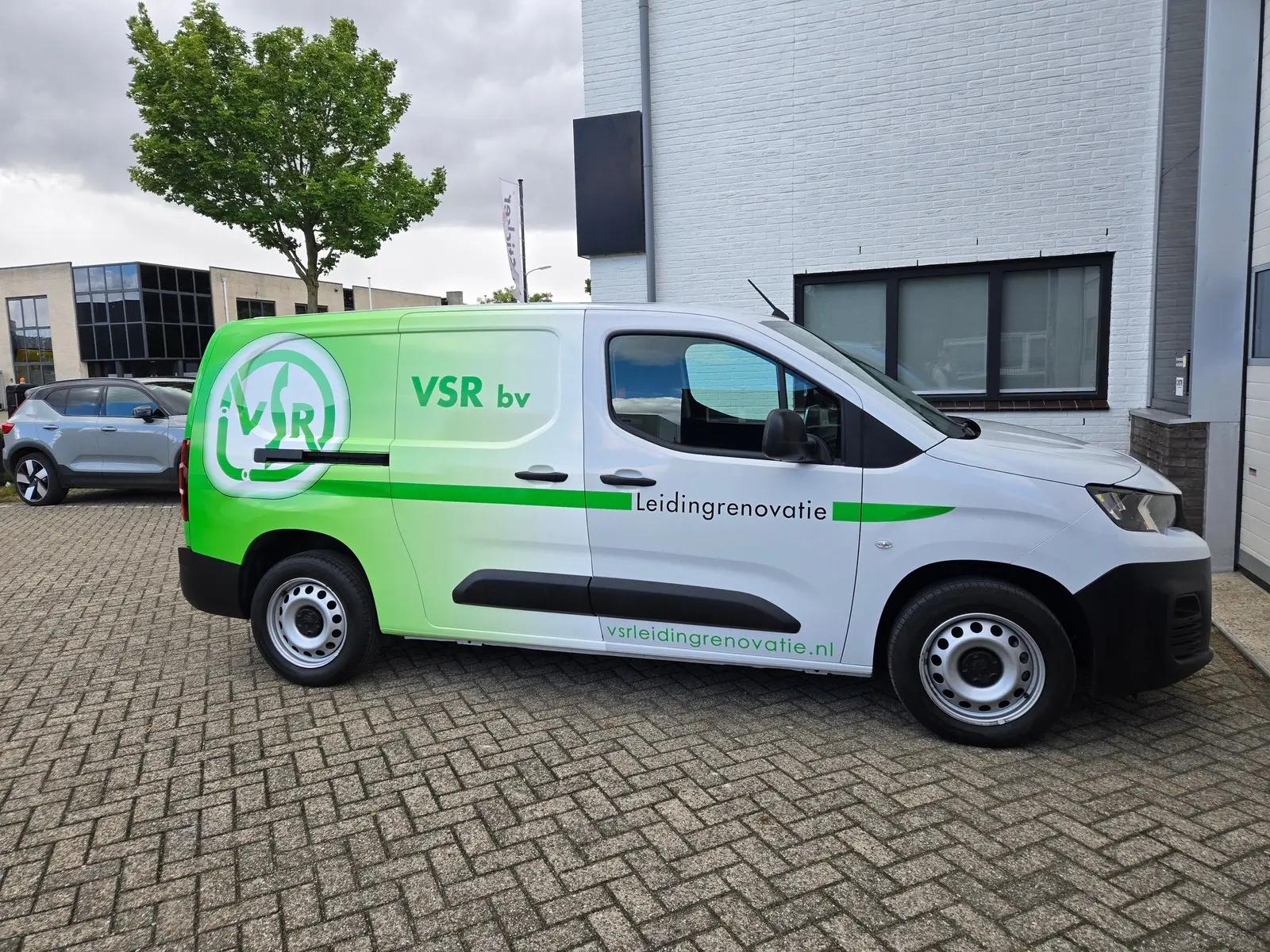 White VSR Peugeot Partner with green panels, a round logo and lettering along the side.